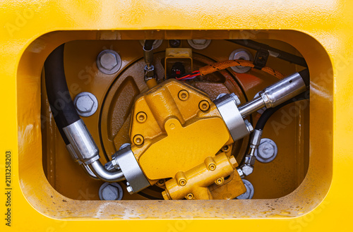 Close up of industrial hydraulic pump and pressure hoses system of heavy yellow construction machinery