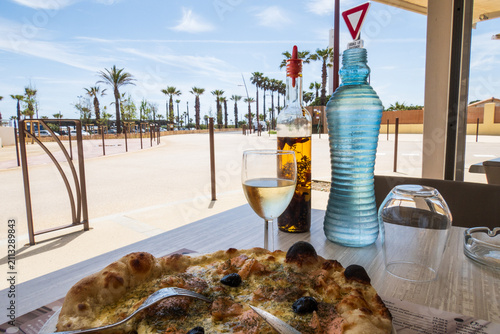 Assis à la terrasse d'une pizzeria, devant une délicieuse pizza, à Port-Barcarès, Occitanie, France.