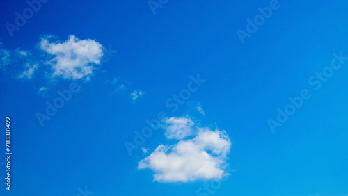 Bild auf Leinwand two lonely white clouds in a vast bright blue sky on a sunny clear day