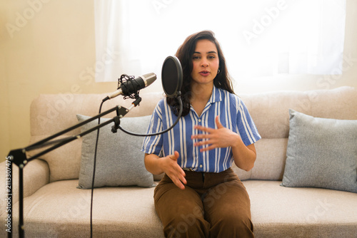 Cuadro en lienzo Young woman recording podcast episode at home, speaking into microphone for onli