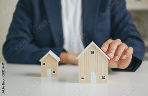 Obraz na płótnie Home insurance protection concept with wooden house models and advisor hand secu