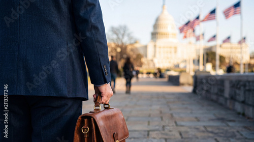 Business professional walking toward the Capitol Building at sunrise with patriotic American flags, illustrating democracy, leadership, government service, and the American dream.