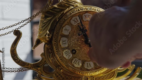 Person winding up an antique golden wall clock