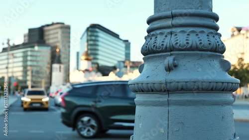 Ornate lamp post in foreground with blurred Moscow city traffic and buildings