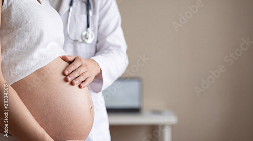 Doctor examining a pregnant woman's abdomen during a prenatal healthcare visit