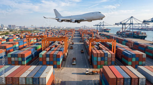 Airplane flying above a vast container terminal, representing international shipping, aviation, supply chains, and global commerce.