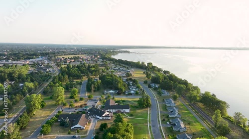 Aerial view of Lake Champlain shoreline near Plattsburgh, New York, featuring forested coastline, calm waters, and scenic mountain backdrop.