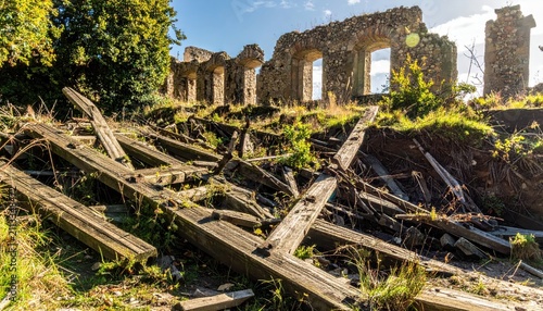 Ruins of an old stone building with collapsed wooden structures in a grassy overgrown landscape