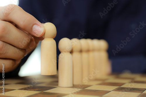 Hand chooses person wooden doll standing leader from group teamwork people for HR human resources officer or business planning relationship or team player and personnel management job performance.