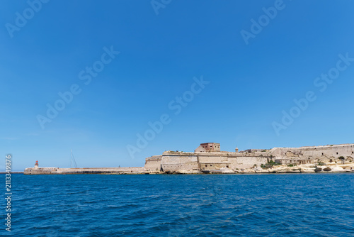 Quadro su tela Historic stone bastions and red beacon lighthouse guarding the harbour entrance
