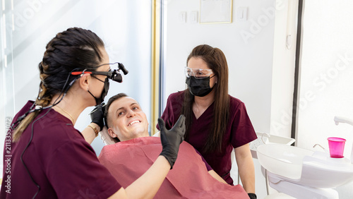 Dental care takes place in a clinic with a patient and two dental professionals