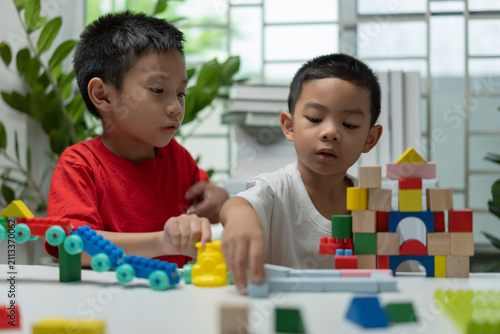 Принти на полотні Two young children playing with colorful building blocks at home, inspiring team