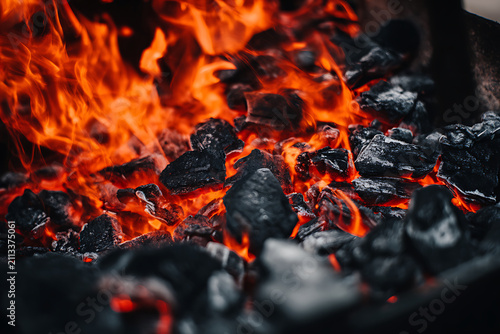 Close-up of glowing hot coals and vibrant flames in a fire pit.