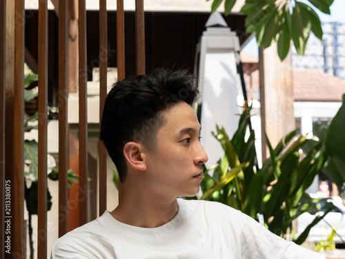 Cuadro en lienzo Young man gazes thoughtfully beyond wooden slats