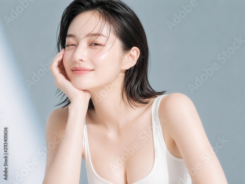 Young Woman Smiling with Dewy Skin Against Soft Blue Studio Background