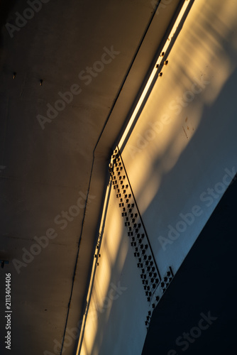 Abstract industrial geometry of concrete bridge underpass with golden sun ray