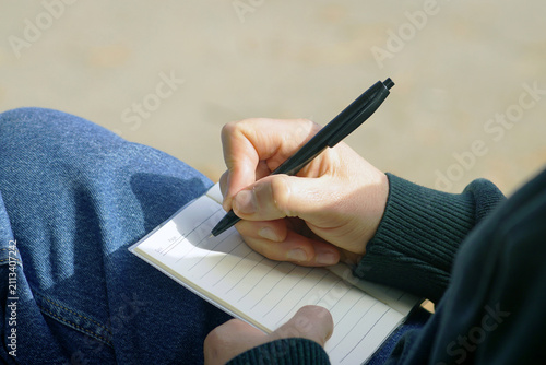 Quadro su tela Hand writing inside pocket notebook while seated comfortably outdoors