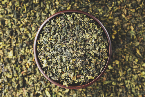 Premium Tieguanyin in dark wooden bowl on green tea pattern background