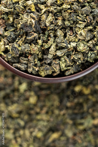 Dark wooden bowl filled with Tieguanyin on tea texture background