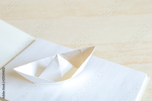 Foto A minimalist white paper origami boat rests on an open notebook page