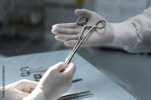 Slika na platnu Surgeon Passing Hemostat Forceps During Surgical Procedure in Operating Room