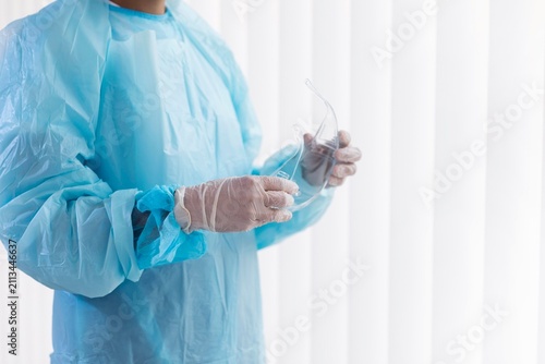 Healthcare Worker Holding Protective Safety Goggles While Wearing PPE Gown