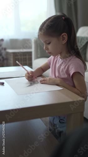 Focused little girl drawing with pencils at home