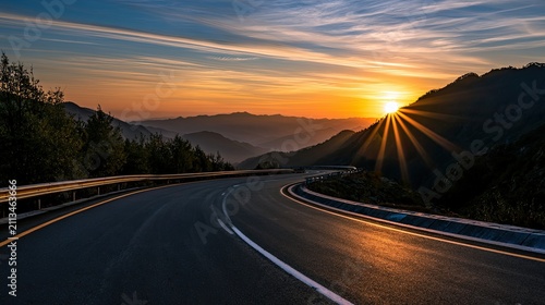 A winding road ascends a mountain as the sun sets, casting a warm glow