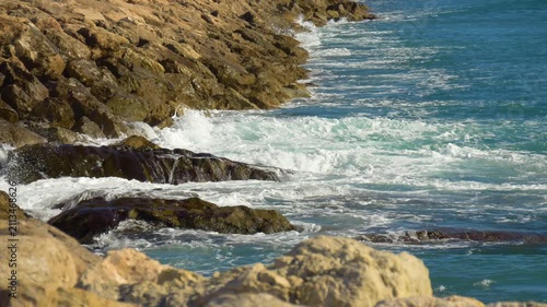 Blue sea waves crashing on rocky coastline