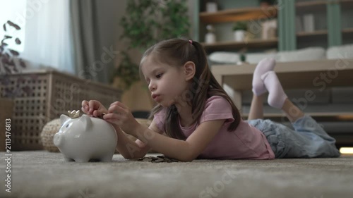 Little girl inserting coins into piggy bank