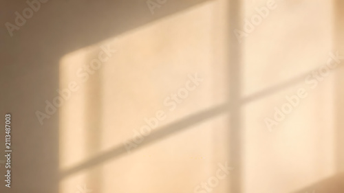 Sharp window frame shadows cast across a smooth beige wall creating soft natural lighting and a minimalist aesthetic mood
