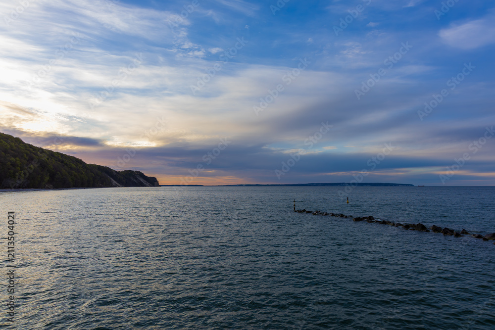 Obraz premium Twilight over Baltic coastline with dark wooded cliffs and serene sea waters