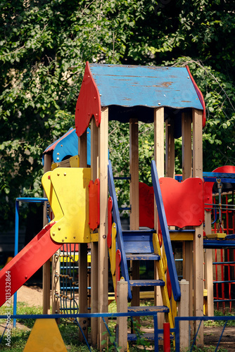 Colorful empty children playground with slides and climbing equipment in a green residential courtyard. Outdoor recreation, childhood, neighborhood amenities and family friendly urban environment.