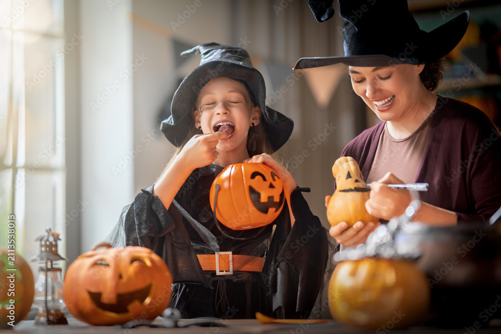 Obraz premium Happy Mother and Daughter in Witch Costumes Celebrating Halloween