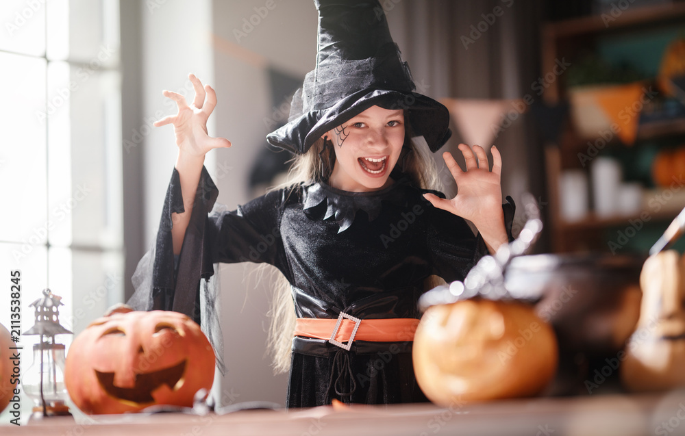 Obraz premium Joyful Girl in Witch Costume Celebrating Halloween with Pumpkins