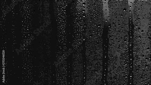 Tableau sur toile Water droplets on dark glass create a textured monochrome pattern with varying s