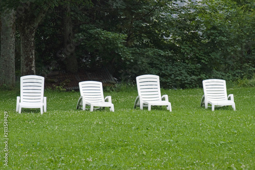 row of white plastic loungers in the park