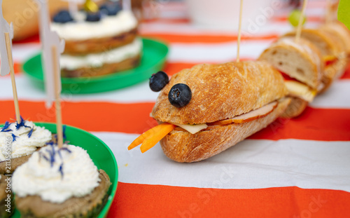 Bild auf Leinwand Creative snake shaped sandwich made with fresh bread, cheese, meat and vegetables, decorated with blueberries and carrot tongue