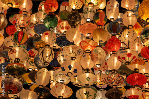 Many Japanese lanterns hung with lights on.