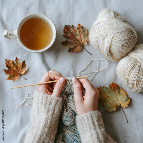 Knitting in a cozy setting with warm tea and autumn leaves in a serene indoor atmosphere