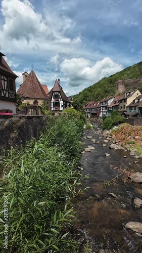 Romantic medieval street in Kaysersberg with half‑timbered houses and vibrant summer flowers in Alsace