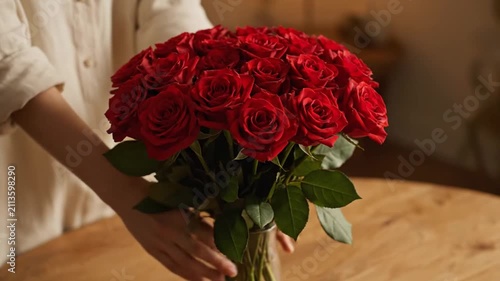 Woman arranging a large bouquet of red roses in a vase
