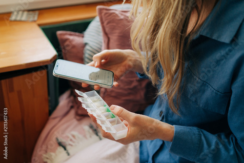 A woman uses a mobile phone for instructions on how to take vitamins and medications.