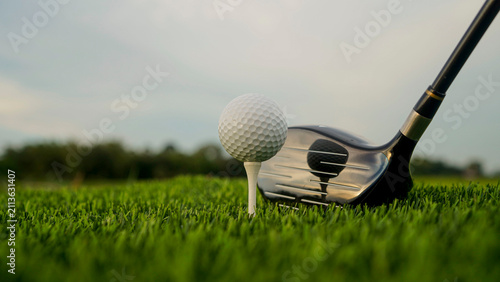 Golf clubs and balls on a green lawn in a beautiful golf course with morning sunshine.