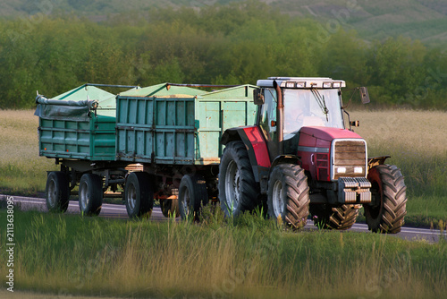 Картината върху платно Tractor and baler working route through green rural landscape