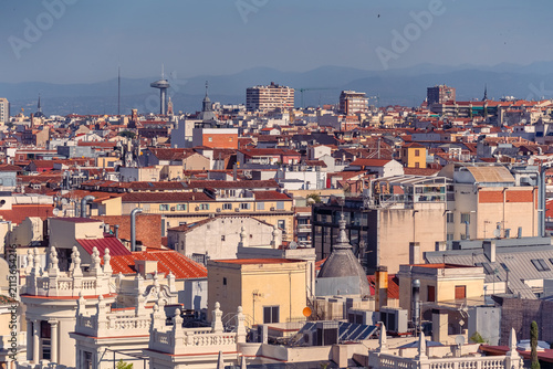 Elevated view over central Madrid rooftops with Faro de Moncloa and distant mountains