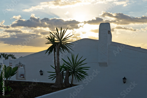 White resort villa at sunset with palm trees and ocean view, Los Cristianos, Tenerife
