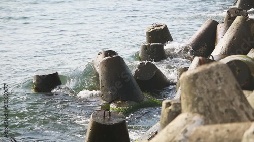 Concrete sea breakwater with weathered tetrapods protecting shoreline under soft daylight