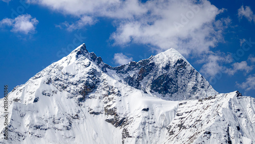 Majestic Snow Covered Mountain Peaks Against Clear Blue Sky, Sharp Glacier Peaks in High Altitude Himalayan Range On a Bright Sunny Day