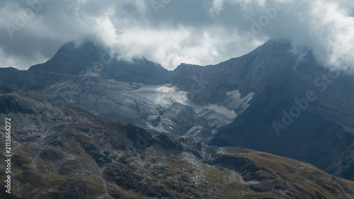 Breathtaking high-altitude landscape in the Valais region of Switzerland, featuring a dramatic, steep green mountain ridge. 